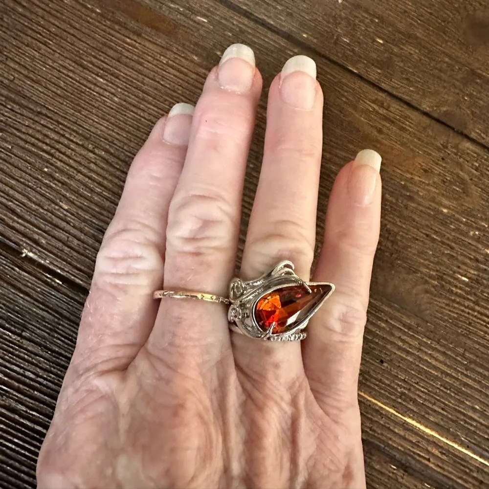 Ring in silver metal intricate with teardrop shaped amber color stone